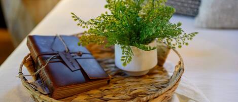 A wicker basket containing a small potted plant and a leather-bound book on a white tablecloth.