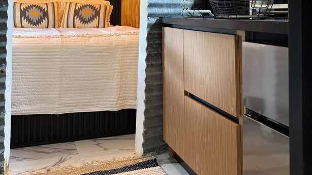 Una cocina compacta con estufa moderna, armarios de madera y una zona de comedor con mesa y sillas.