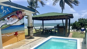Un espace piscine offrant une vue sur l’océan, un coin salon abrité et une fresque représentant la vie marine.