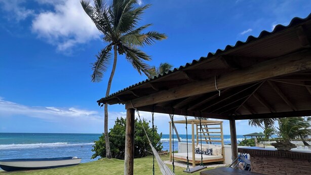 Une terrasse au bord de la plage, avec un hamac, une plateforme en bois et une vue sur l’océan.