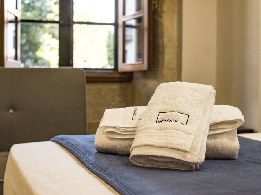 Un letto rifatto con asciugamani bianchi piegati e una coperta blu.