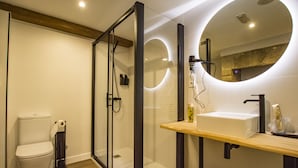 A modern bathroom with a glass-enclosed shower, a white toilet, and a wooden vanity with a mirror. - NÓMADE SANTIAGO (Santiago de Compostela)