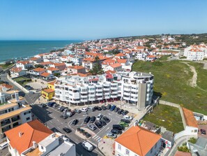 Ein Küstenwohngebiet mit mehrstöckigen Gebäuden, einem Parkplatz und freiem Blick auf das Meer.