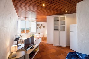 Un espace de vie compact comprenant un coin cuisine, un coin repas et une vue sur la mer.