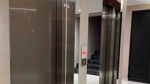 A modern elevator area with metallic elevator doors and a control panel.