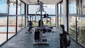 A gym with exercise equipment, large windows, and a view of the outside.