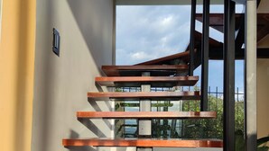 Un escalier moderne avec des marches en bois et des rampes en métal, menant à l’étage supérieur.