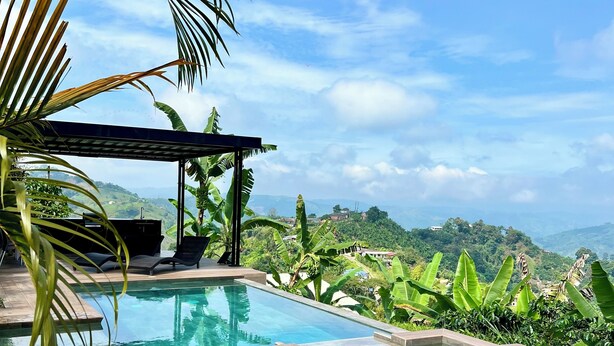Un espace piscine agrémenté d’une pergola, de chaises longues et offrant une vue sur le paysage environnant.