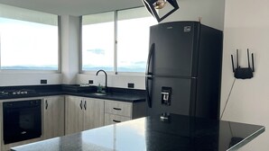 Une cuisine moderne avec un réfrigérateur noir, des armoires en bois et un grand îlot central.