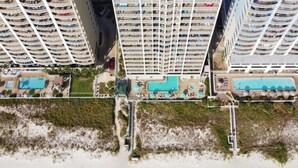 Ein Hochhotel mit mehreren Balkonen, einem zentral gelegenen Pool und Strand.