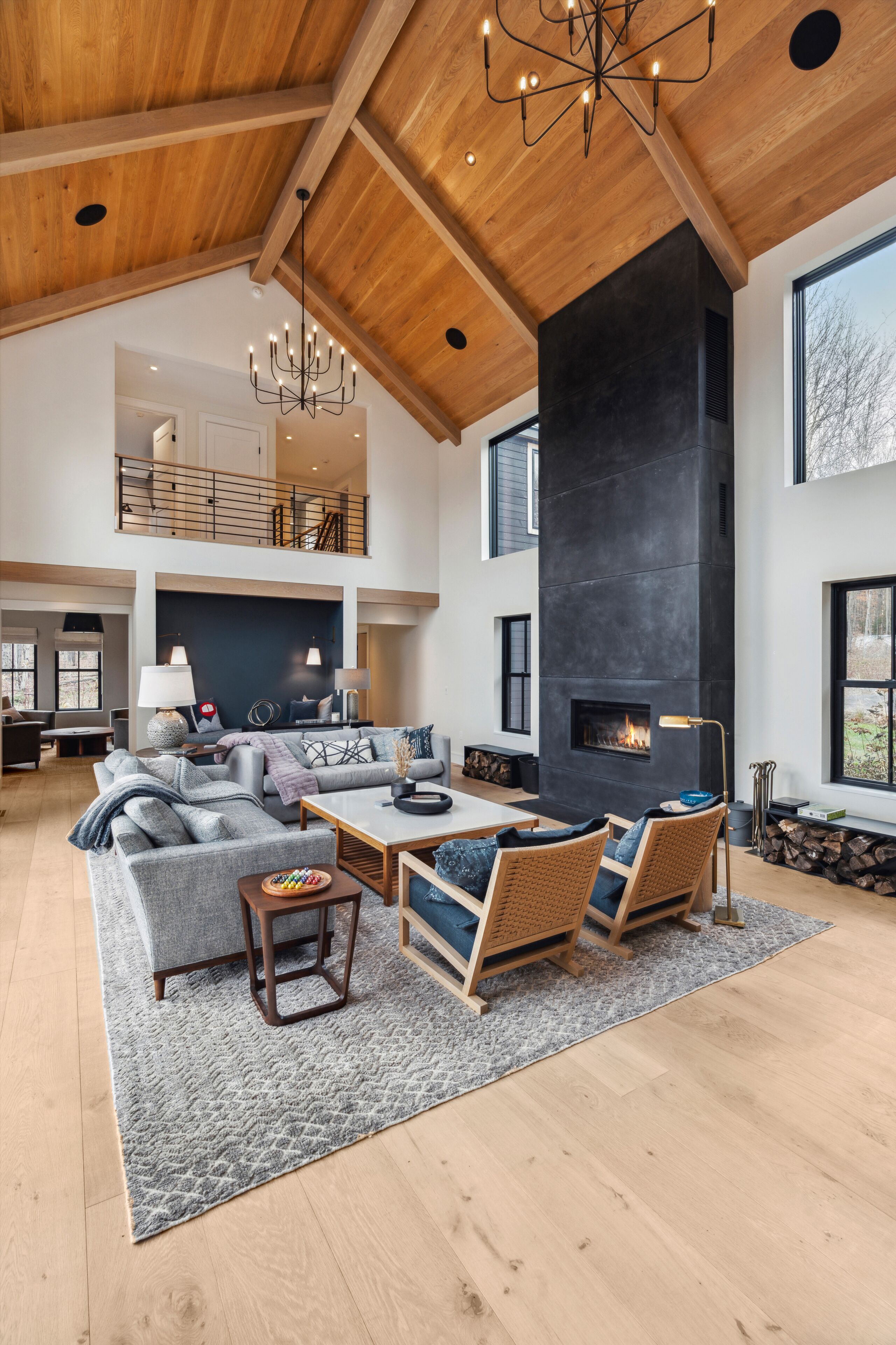 A spacious living area with a high ceiling, a fireplace, and a large window.