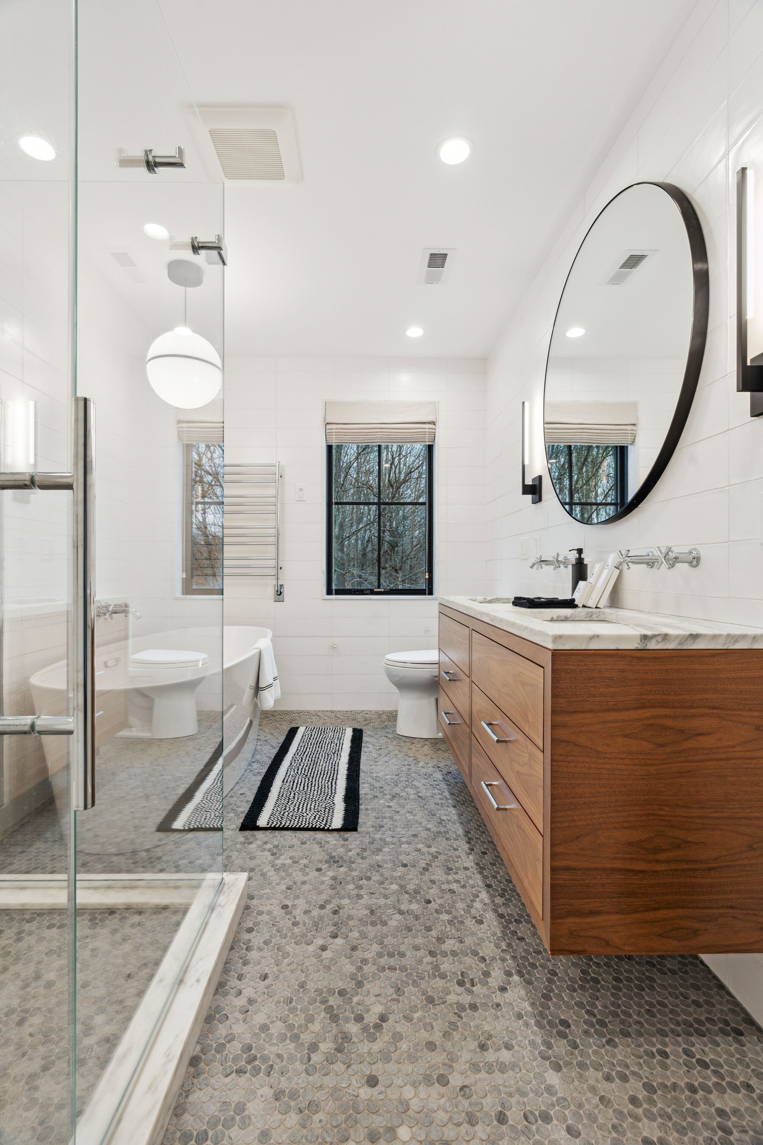 Une salle de bain moderne avec une douche à parois de verre, un meuble-lavabo en bois et un grand miroir.