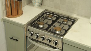 A kitchen with a gas stove, a microwave, and a small oven. There are knives in a wooden block on the counter.