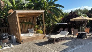 A patio area with a wooden pergola, a grill, and seating arrangements.