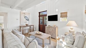 Un espacio habitable amplio con un sofá, una mesa de comedor y un televisor montado en la pared.