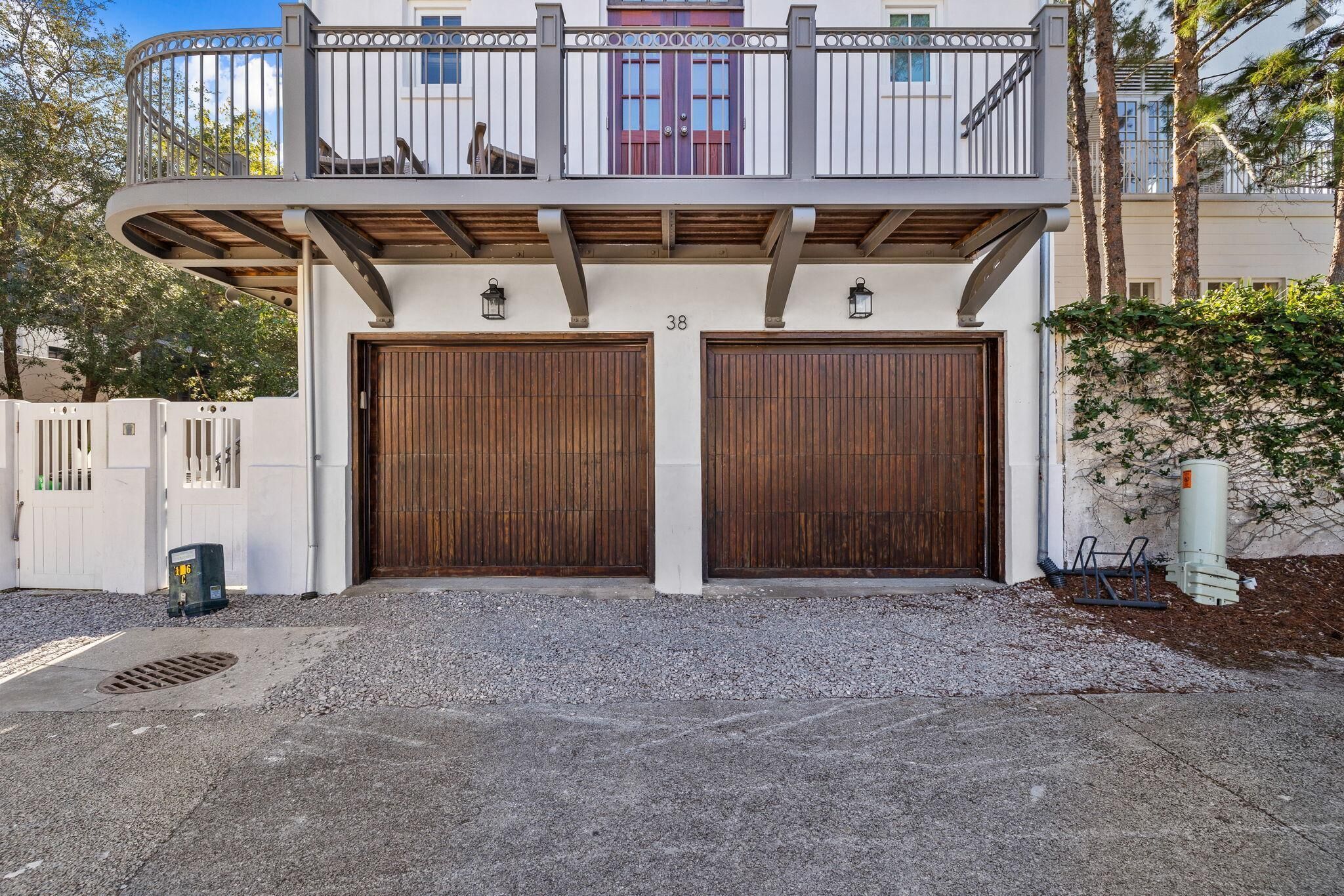 Een tweelaags huis met een balkon, twee garagepoorten en het getal '38' op de gevel.