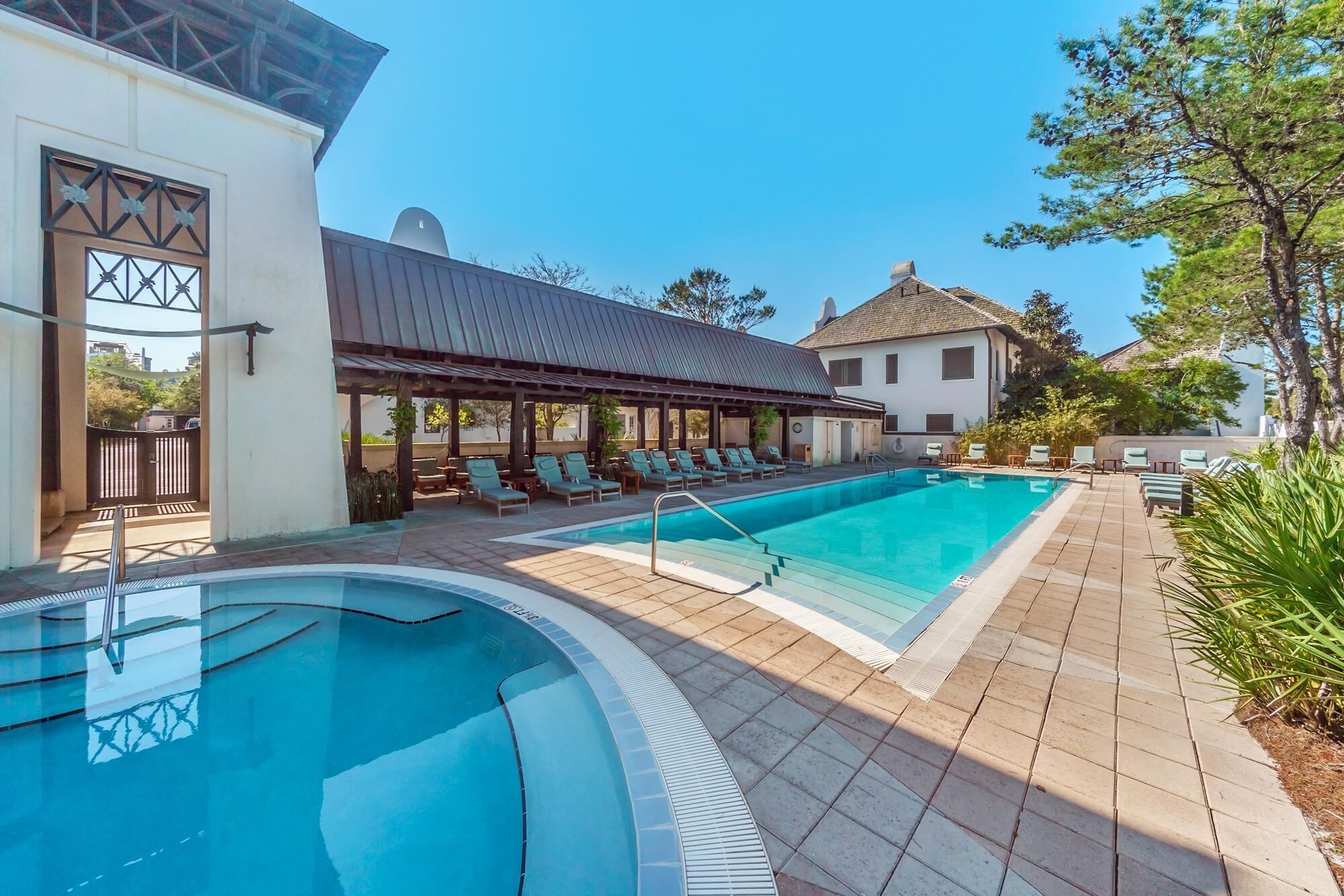En pool med solstolar och ett avskärmat område med sittplatser.