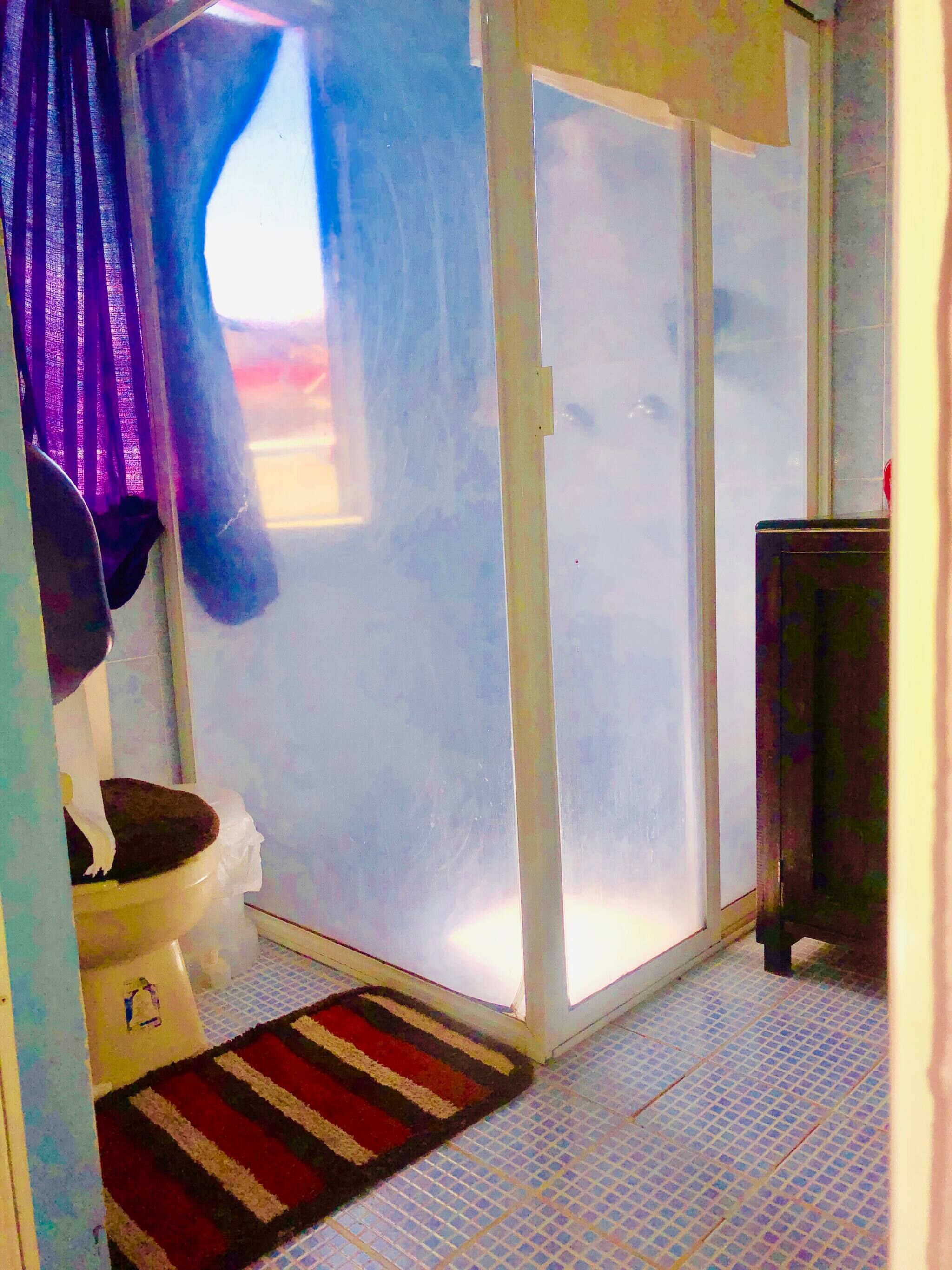 A bathroom with a toilet, a shower area, and a tiled floor.