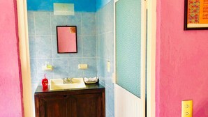 A bathroom with blue tiles, a wooden cabinet, a sink, and a mirror. - Room-central Comfy Small Studio (San Cristóbal de las Casas)