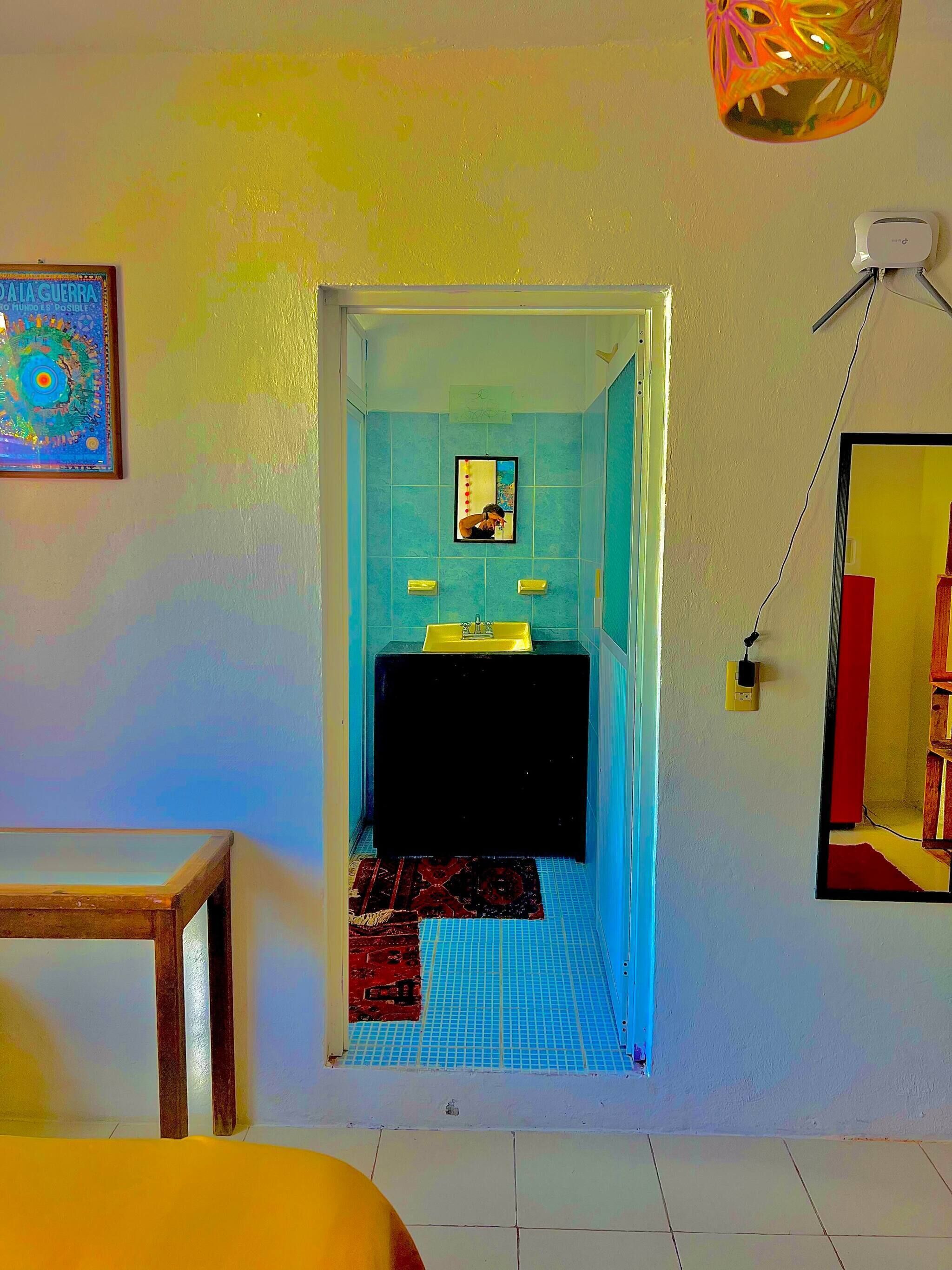 A bathroom with a blue-tiled floor, a black sink, and a mirror above it.