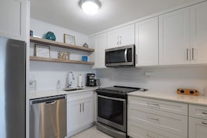 Una cocina moderna con armarios blancos, electrodomésticos de acero inoxidable y un microondas integrado.