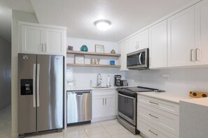 A modern kitchen with white cabinetry, stainless steel appliances, and a built-in microwave.