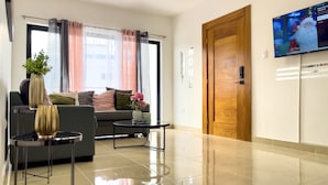 Una sala de estar moderna con un sofá, una mesa de centro y un televisor montado en la pared.