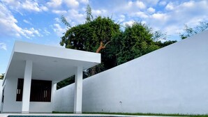 Un área de piscina moderna con un edificio blanco y un árbol al fondo.