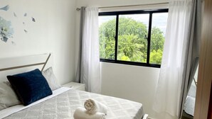 Un dormitorio con cama, ventana con cortinas y vistas a zonas verdes.