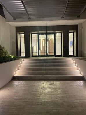 Une entrée moderne, avec un escalier menant à une porte dotée de panneaux de verre.