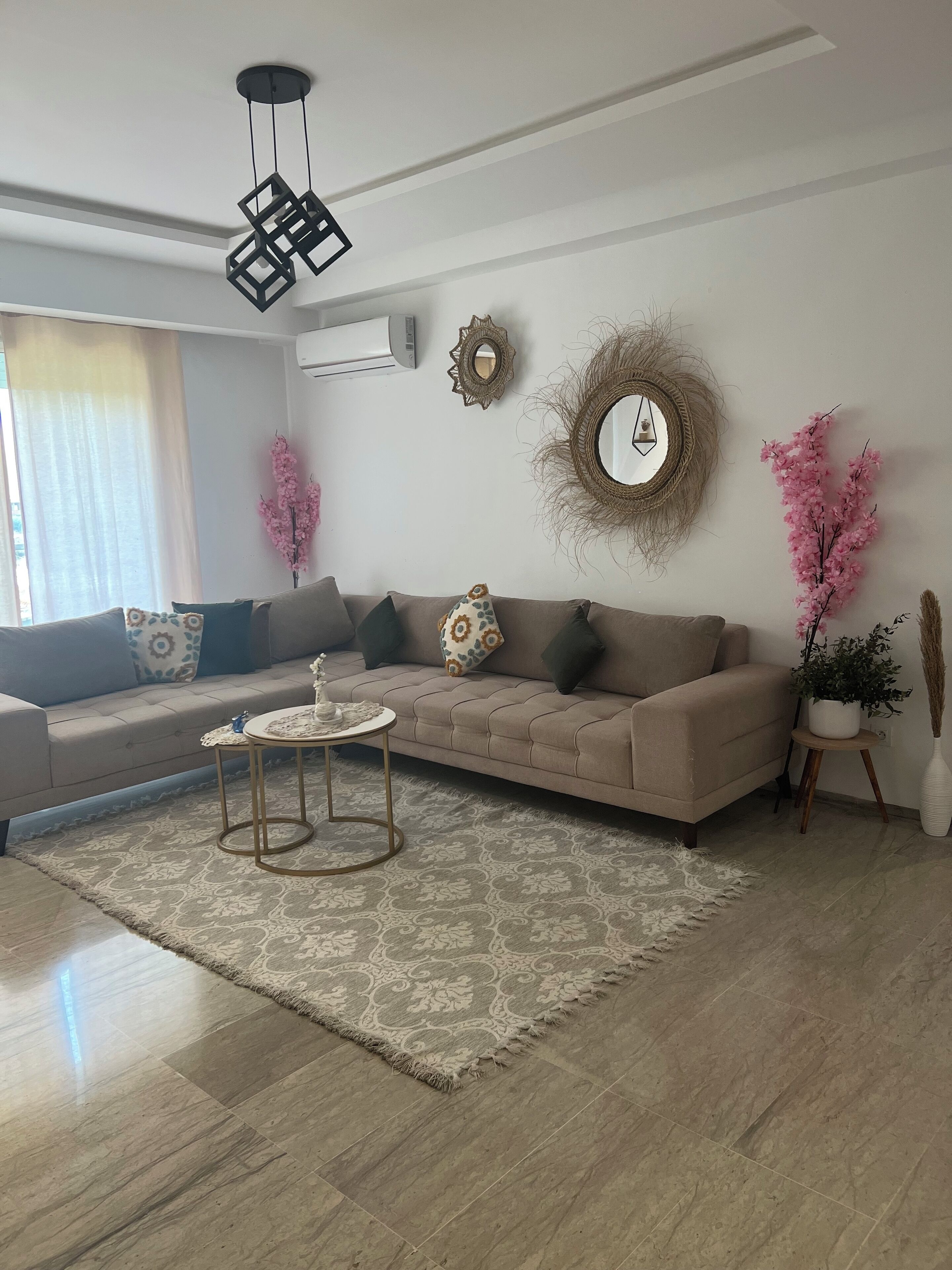 Un salon moderne avec un canapé beige, un tapis à motifs et des coussins décoratifs.