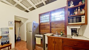 A compact kitchen with a refrigerator, stove, sink, and wooden cabinets. - Beautiful cabin nestled in tropical surroundings on the Banks of the Sitee River (Hopkins)