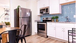 A modern kitchen with stainless steel appliances, white cabinets, and a blue geometric backsplash. - Artist's Bungalow- 1/2 mi from Covington Square (Covington)