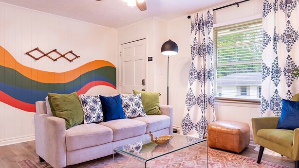 A modern living room with a sofa, ottoman, and a glass coffee table. - Artist's Bungalow- 1/2 mi from Covington Square (Covington)