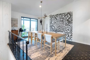 A dining area with a table and chairs, a staircase, and a patterned wall.