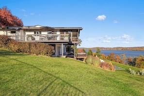 A two-story house with a balcony, a lawn, and a lake view.