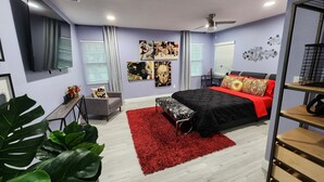 A modern bedroom with a bed, a desk, and a TV.