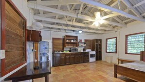 Una cocina compacta con gabinetes de madera, dispensador de agua y microondas.