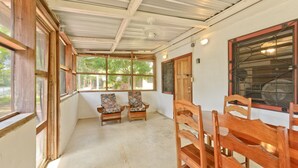 Una habitación con sillas de madera, una mesa y ventanas amplias.