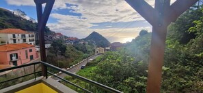 A view from a balcony overlooking a hillside with buildings and a road.