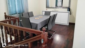 A dining area with a table, chairs, a wooden staircase, and a mirror above the counter. - Casa sousa (Campanario)