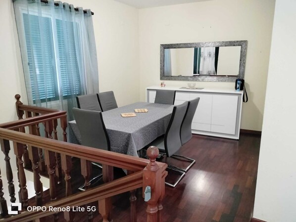 A dining area with a table, chairs, a wooden staircase, and a mirror above the counter.