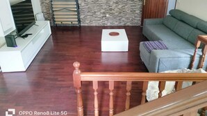 A living room with a wooden floor, a grey sofa, a white coffee table, and a TV on a white stand. - Casa sousa (Campanario)