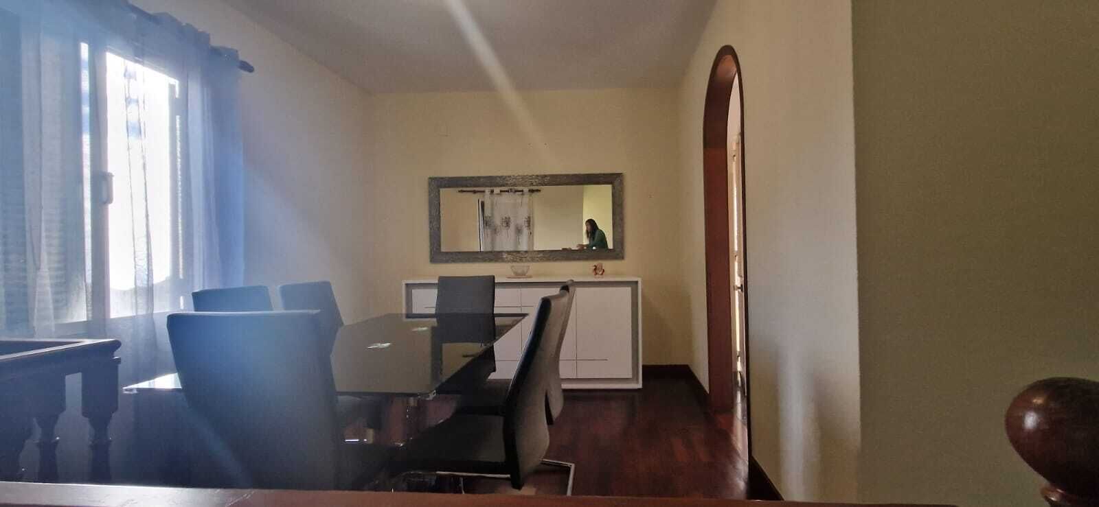 Een eethoek met een tafel en stoelen, een kleine kitchenette en een spiegel aan de muur.