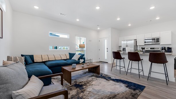 A modern living room with a sectional sofa, a coffee table, and a bar area with stools. - Dog Parks • Museums • Walking and Biking Trails (Centerton)