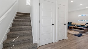 A staircase with carpeted steps leading to a white door. - Dog Parks • Museums • Walking and Biking Trails (Centerton)
