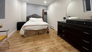 A bedroom with a bed, a dresser, a mirror, and a window. - Central location, easy dining, Edgemont Village, Rec Centre, & Park Royal Mall.
 (North Vancouver)