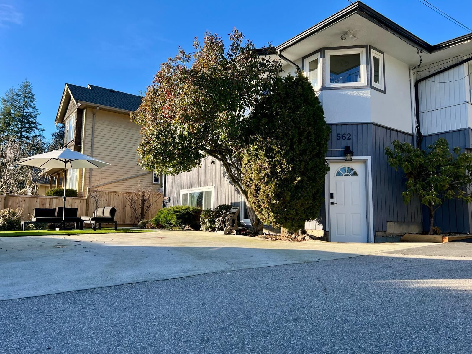 A two-story house with a garage, a covered patio, and a well-maintained lawn.