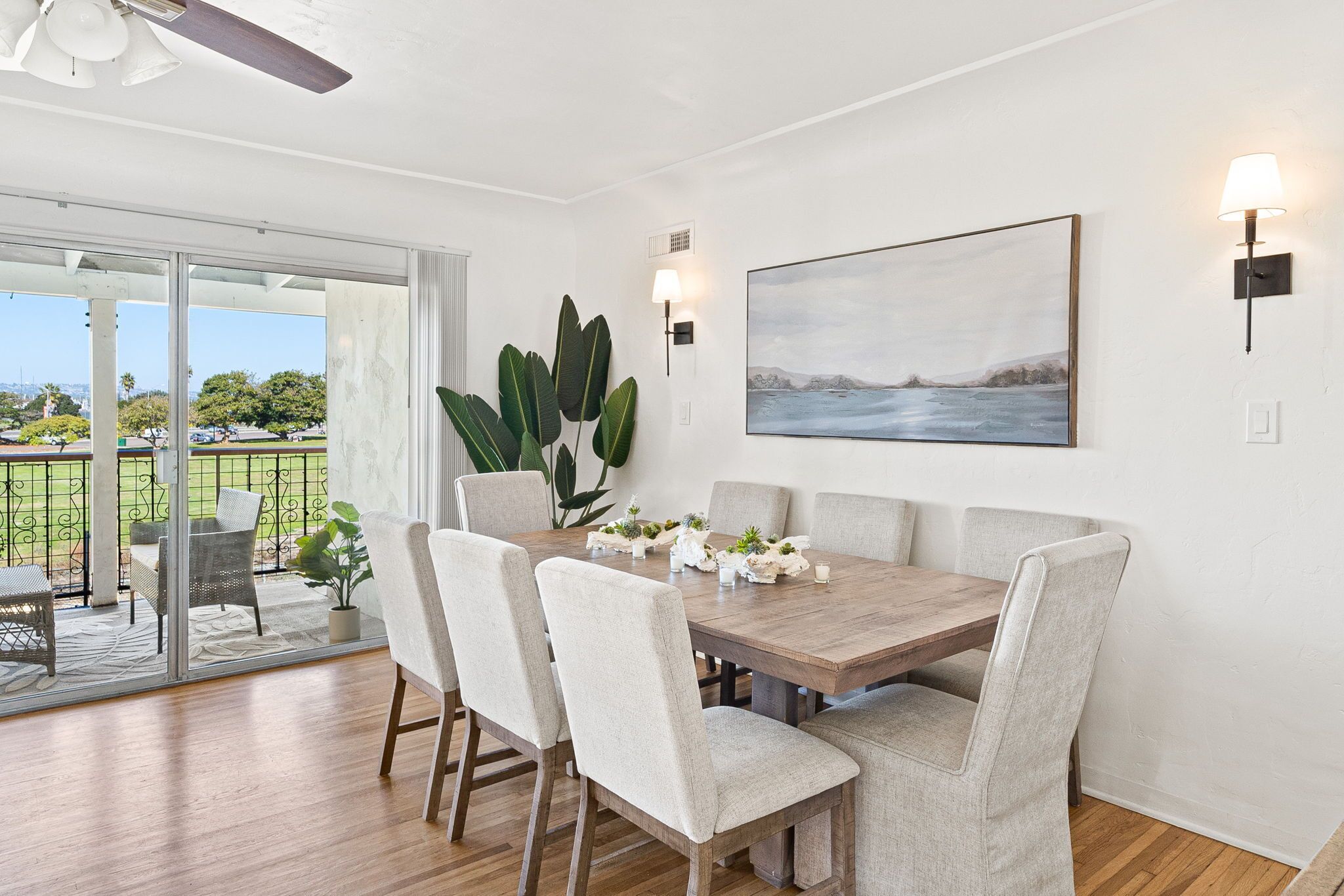 Un espace repas avec une table en bois, des chaises rembourrées et une vue sur l’extérieur.