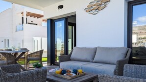 A modern outdoor living area with a sofa, wicker chairs, a dining table, and a coffee table with breakfast items. - PANORAMIC pool & mountains house (Finestrat)